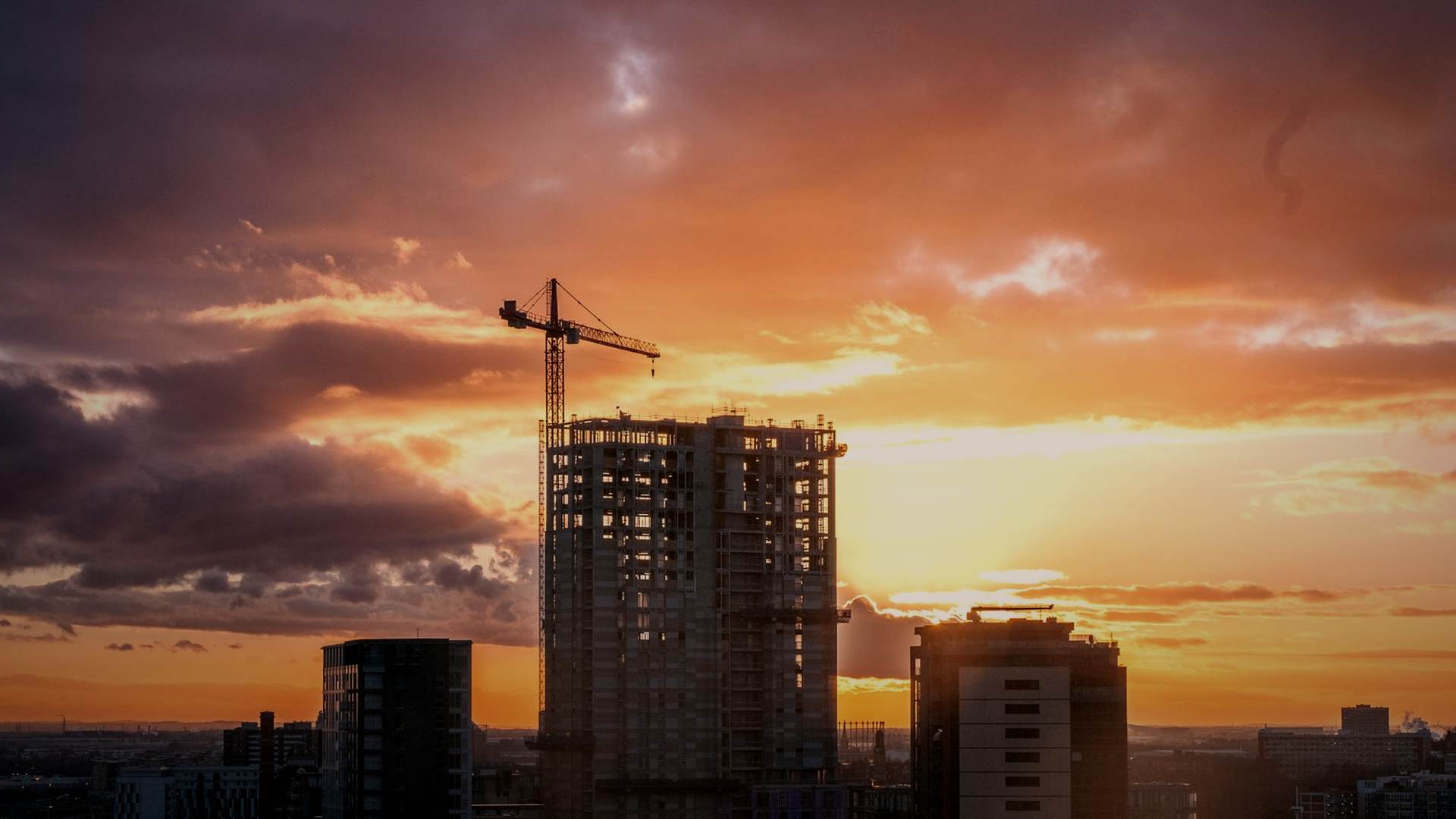 Tower crane over a commercial building frame at dusk in a UK city