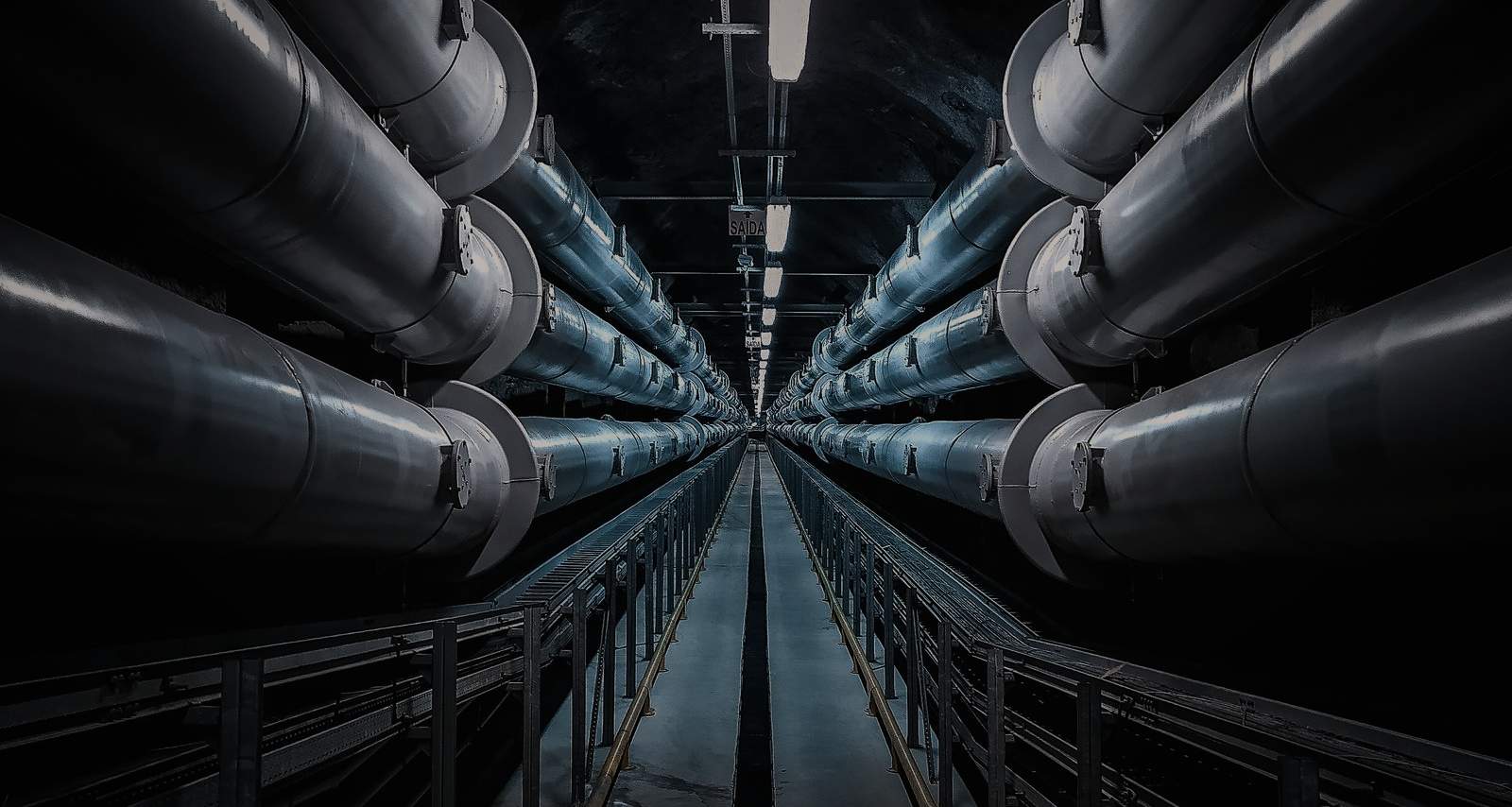 Services tunnel with insulated pipework receding into darkness